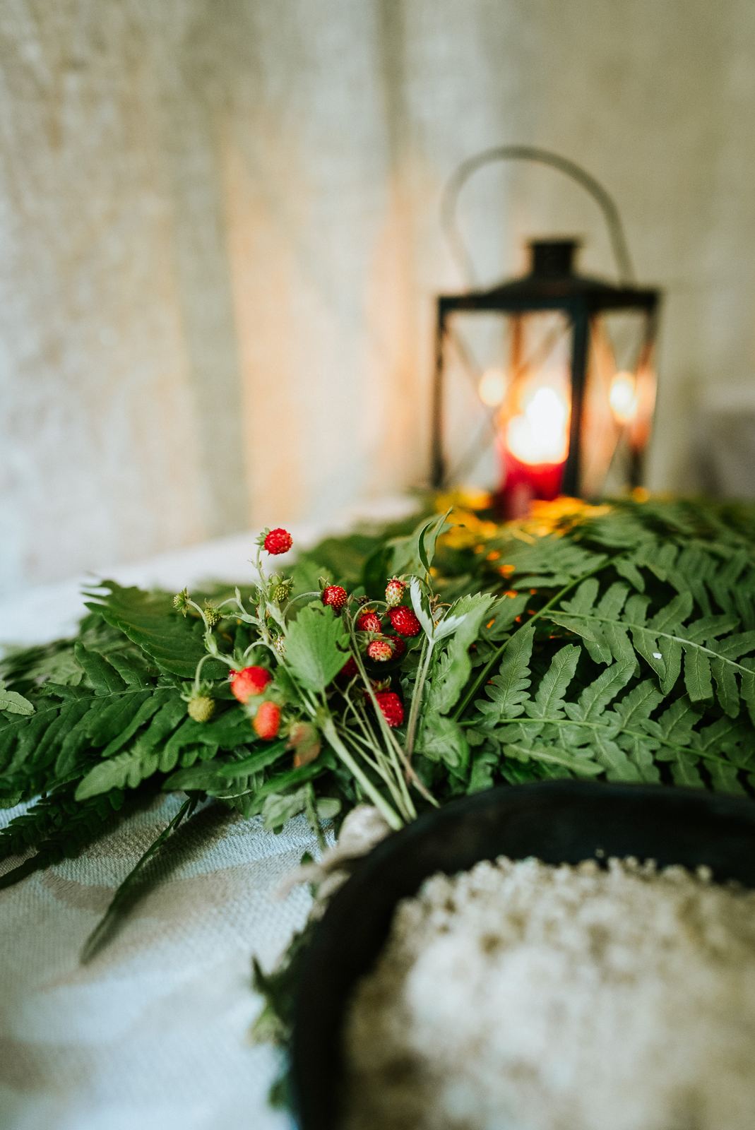 Wild strawberries and ferns on the ritual table, a lantern behind